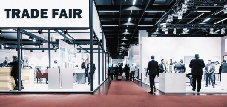 Crowd of people walking between trade show booths with a banner